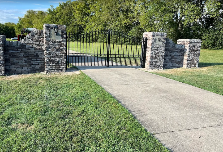 Stone entry columns with iron driveway gate