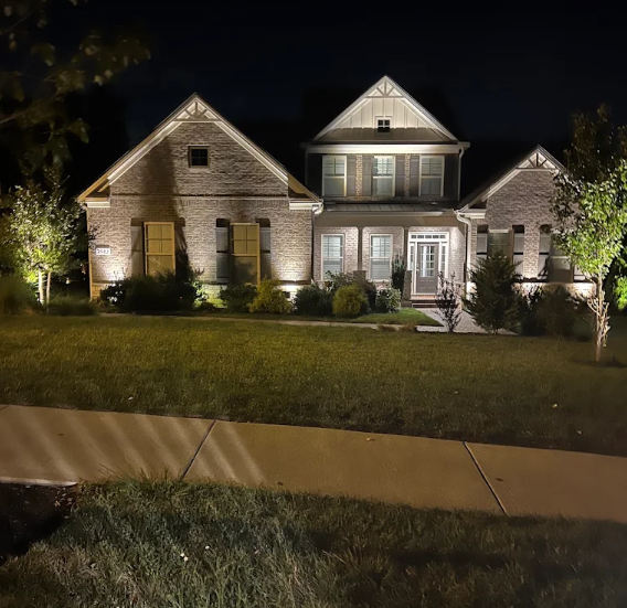 Home facade washed with warm landscape lighting at night