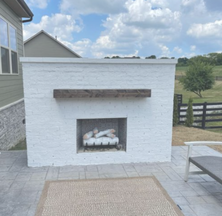 White brick outdoor fireplace on a stamped patio