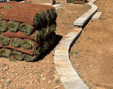Fresh sod pallets beside new stone curbing