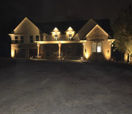 Two-story home lit with uplighting and path lighting