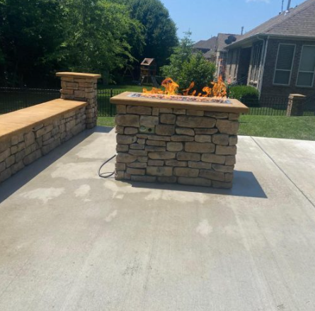 Stone gas fire feature on a concrete patio