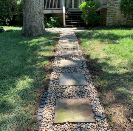 Stone paver path set in river rock across a shaded lawn