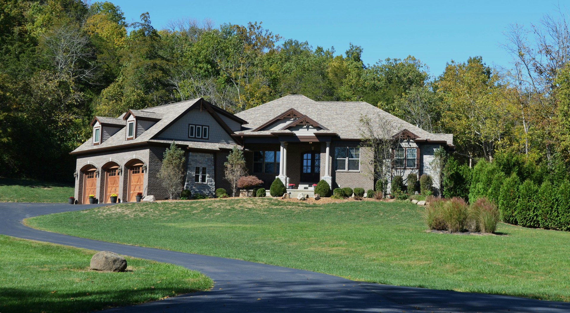 Beautiful modern country home with manicured green lawn and paved driveway